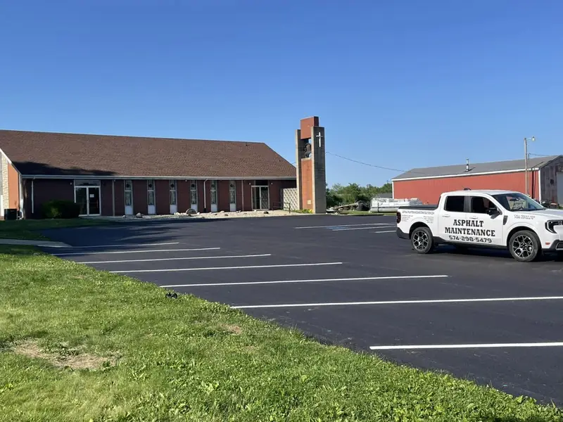 Finished church parking lot with fresh white stall lines and the company pickup parked on the new surface