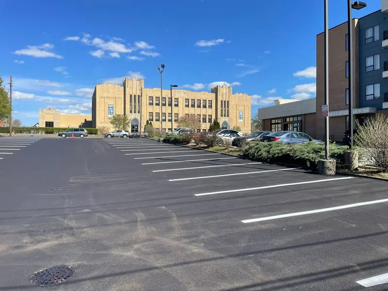 Rows of new white stall lines on a freshly paved lot beside a large historic building