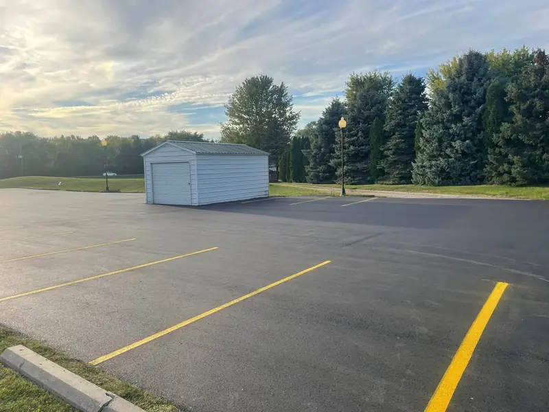 Crisp yellow stall lines on a freshly paved lot beside a detached garage
